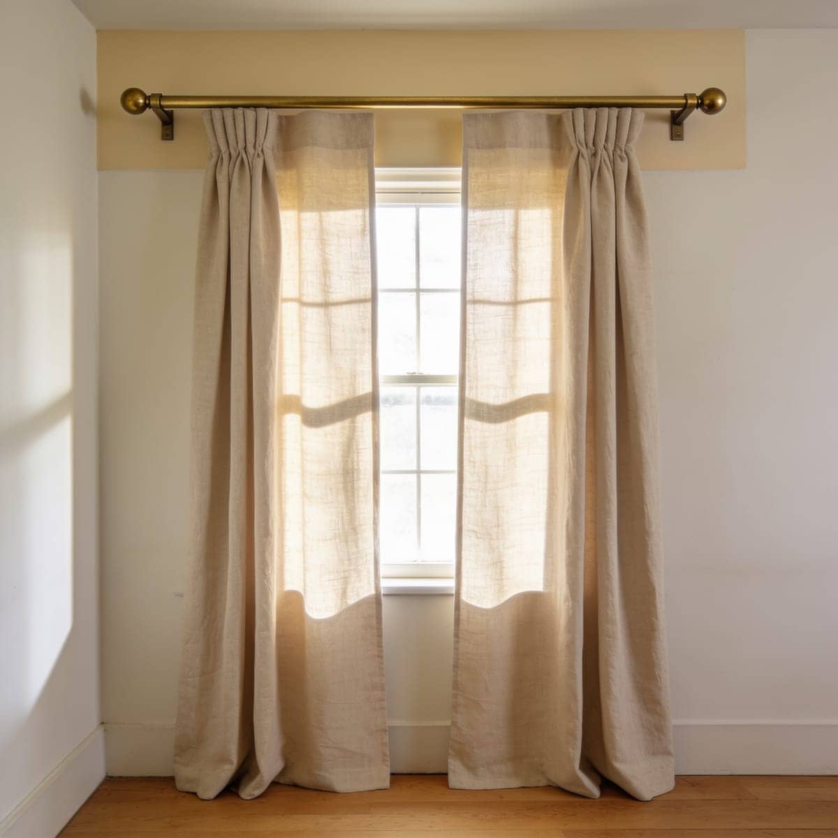 brushed brass curtain rod against a warm cream wall
