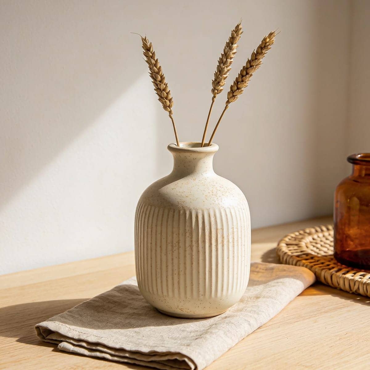 matte cream ribbed ceramic vase holding dried grasses on a mantel