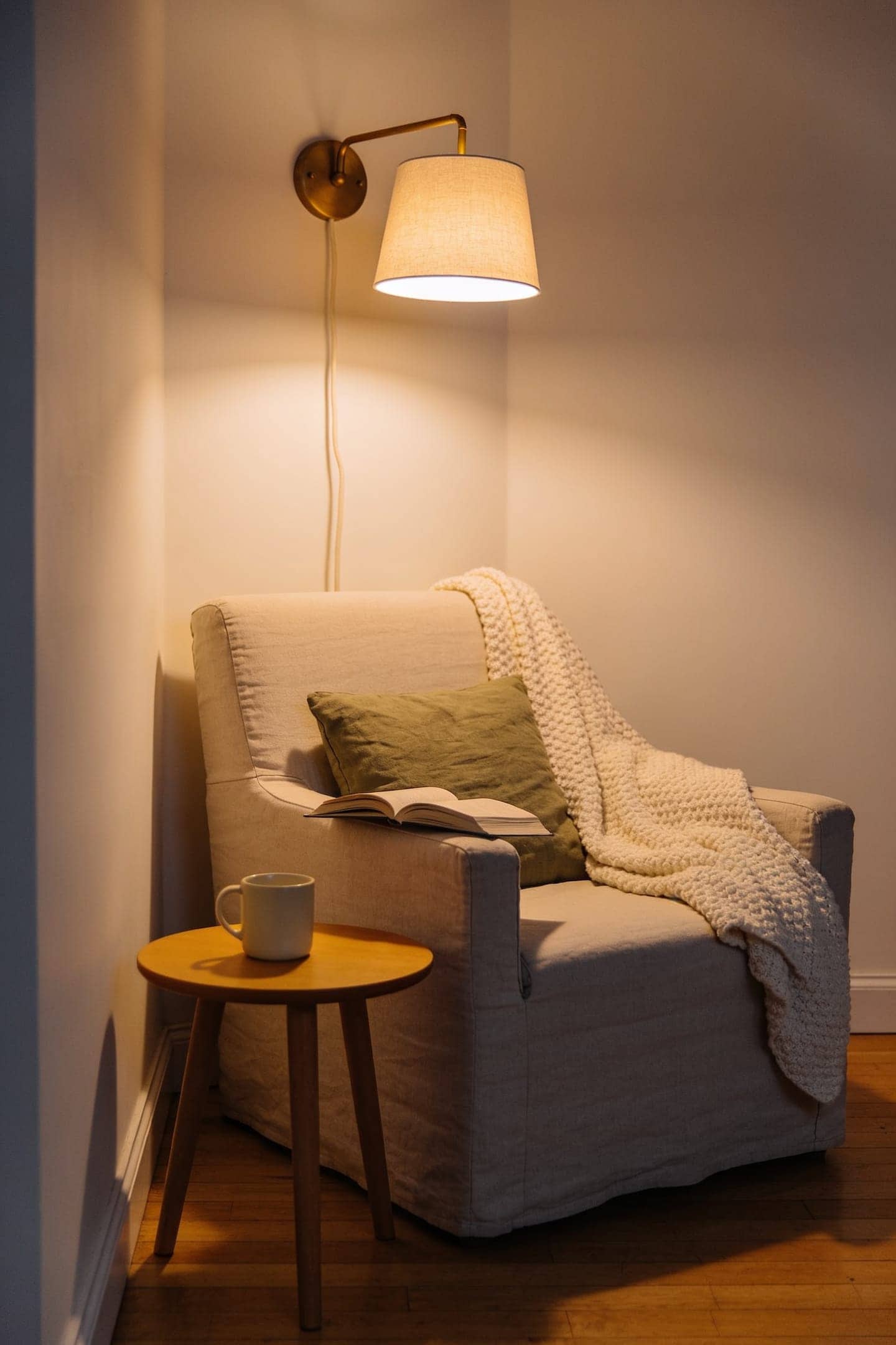 pair of plug-in wall sconces with linen shades glowing warm on either side of a sofa, cords running neatly down the wall
