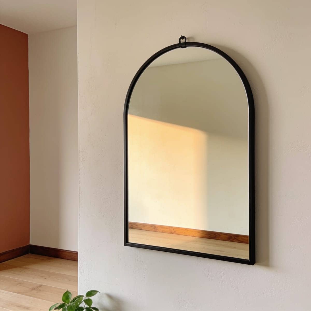 matte black framed arched mirror on a pale warm wall