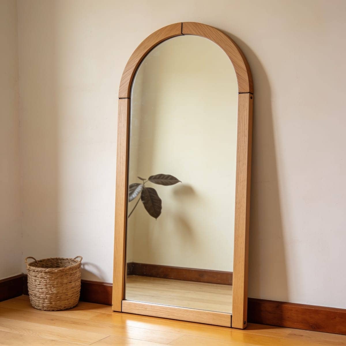 natural oak wood framed arched mirror leaning on a neutral wall