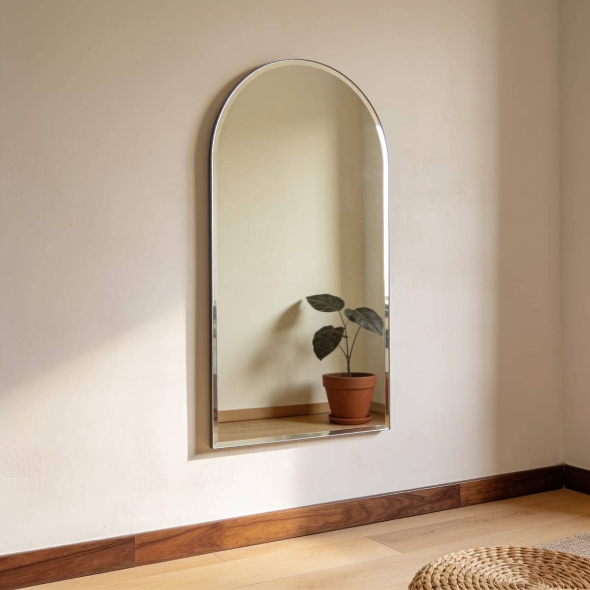 frameless arched mirror with a soft beveled edge on a warm plaster wall