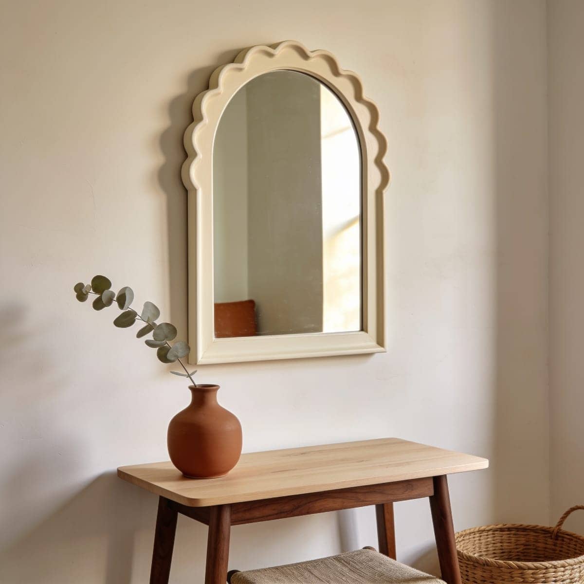 scalloped edge arched mirror in a soft vintage finish above a small table