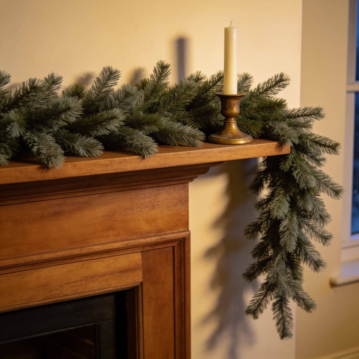 full faux pine garland draped along a wood mantel with candles