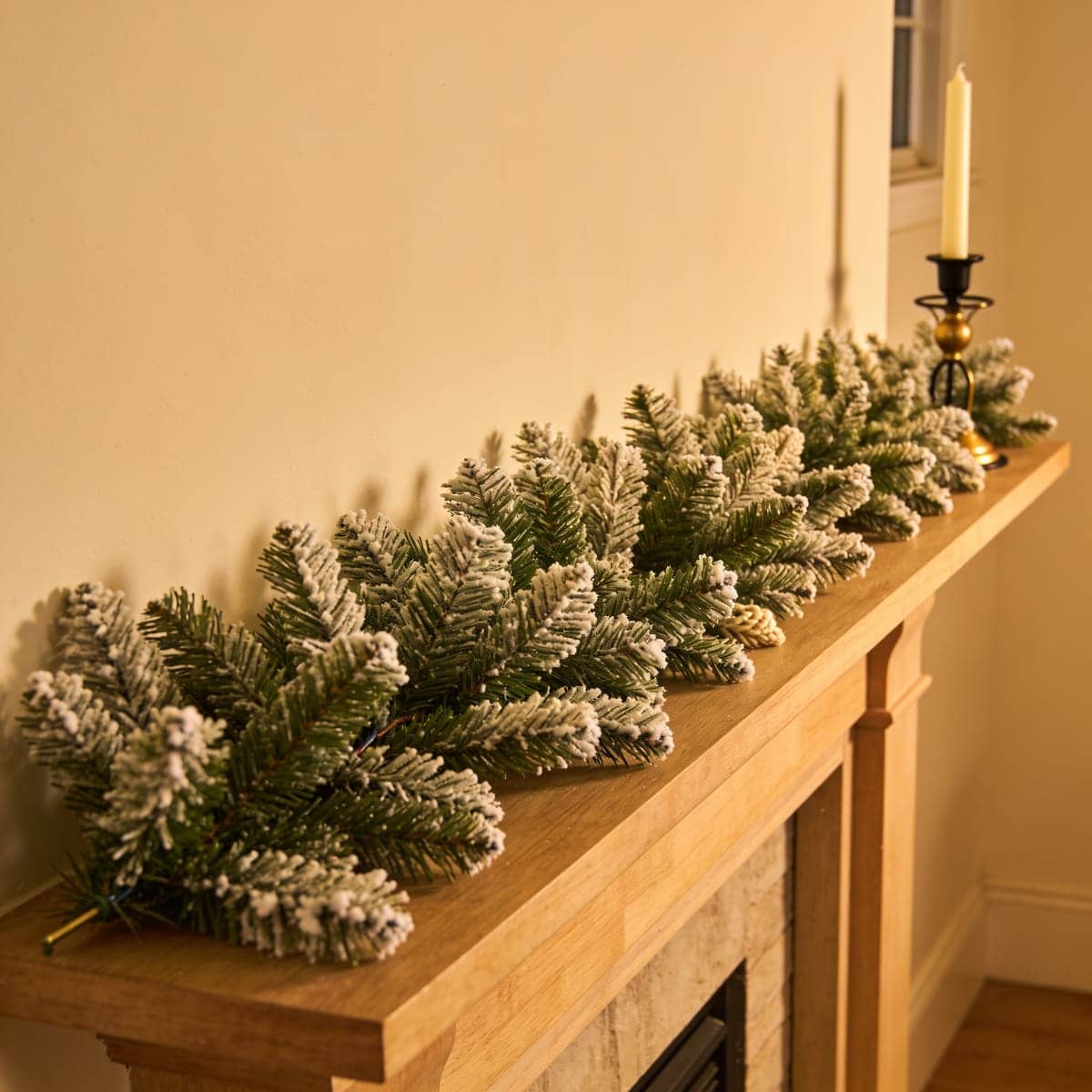 flocked snowy garland with white tipped branches on a shelf