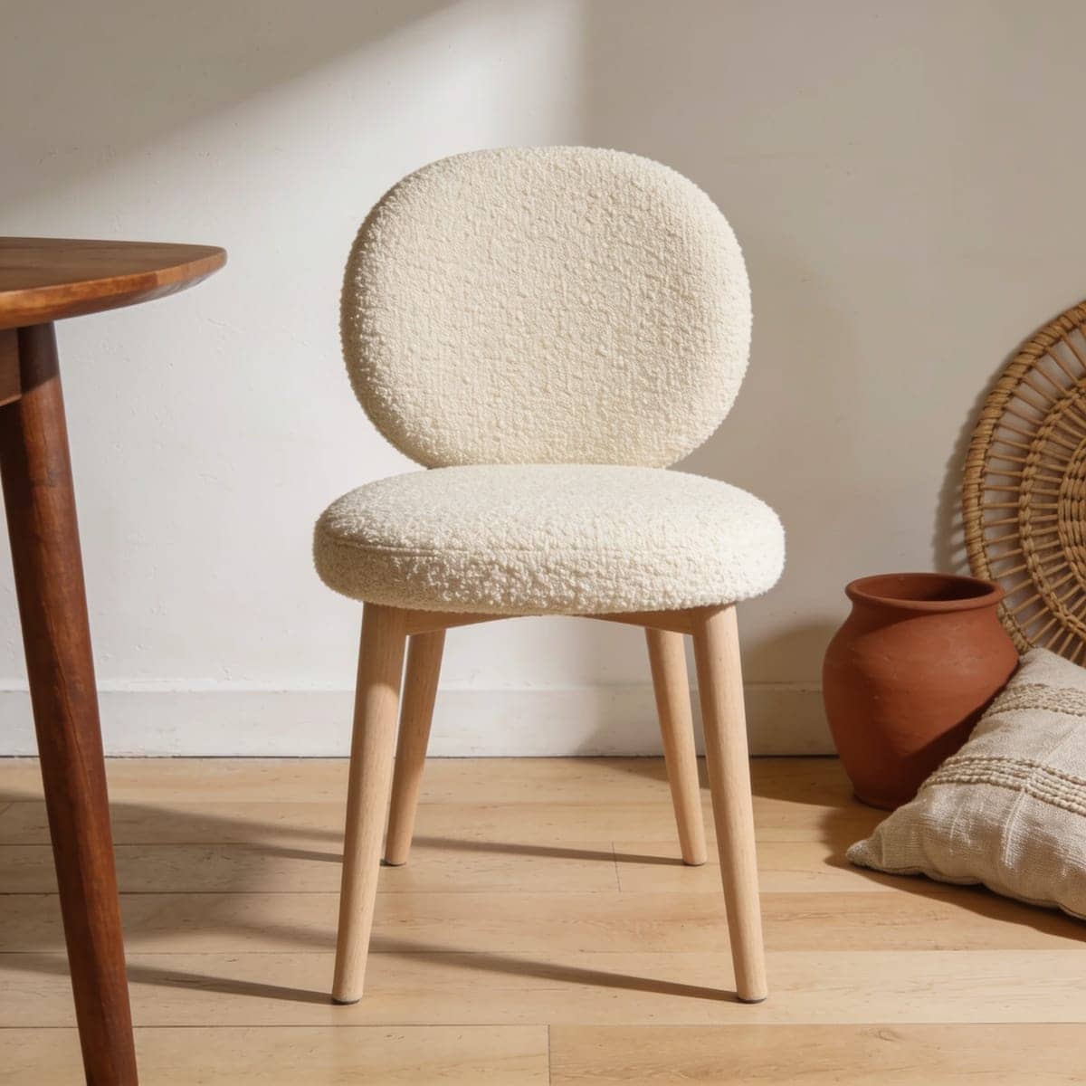 two boucle upholstered dining chairs with slim wood legs at a round dining table