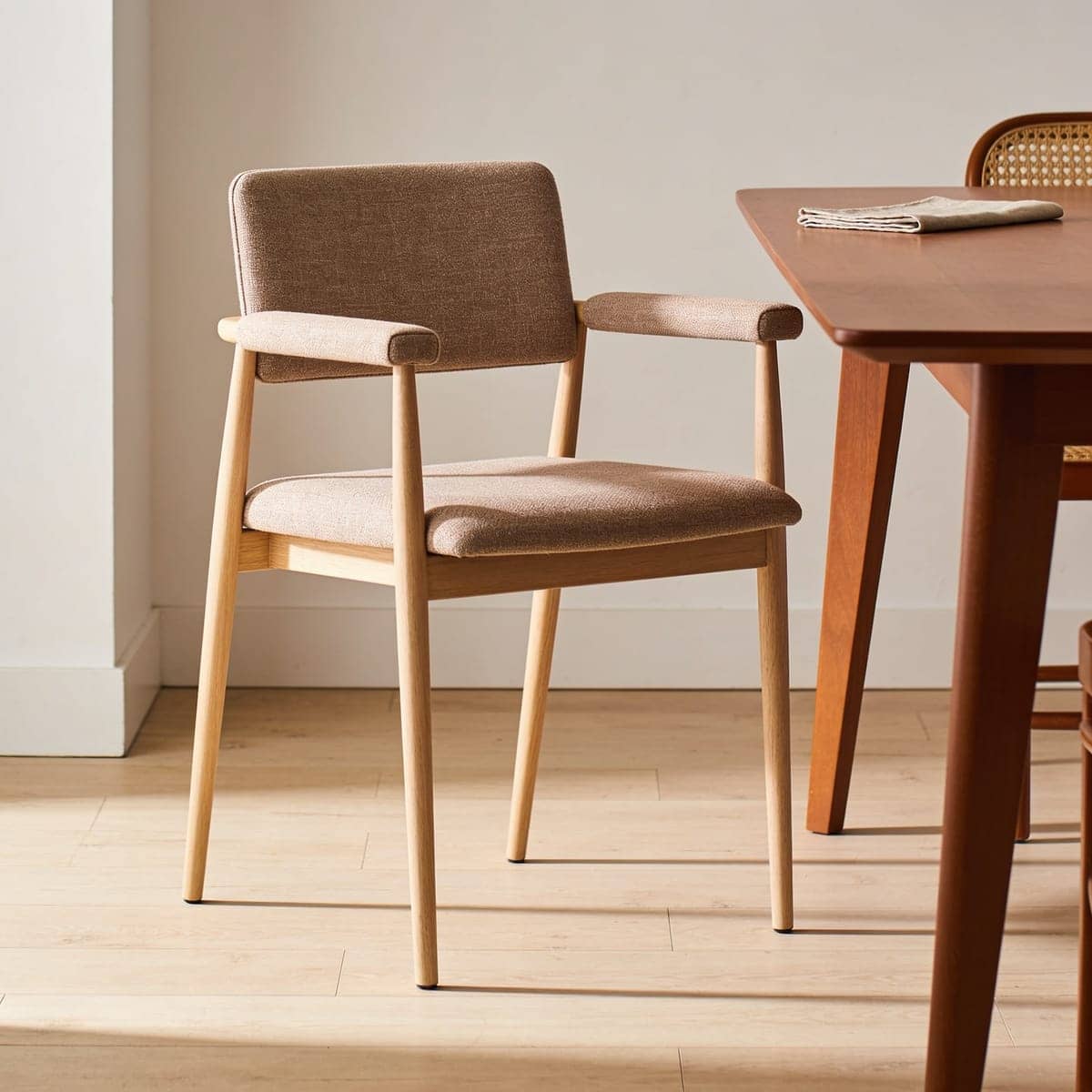 single upholstered dining arm chair at the head of a wood table