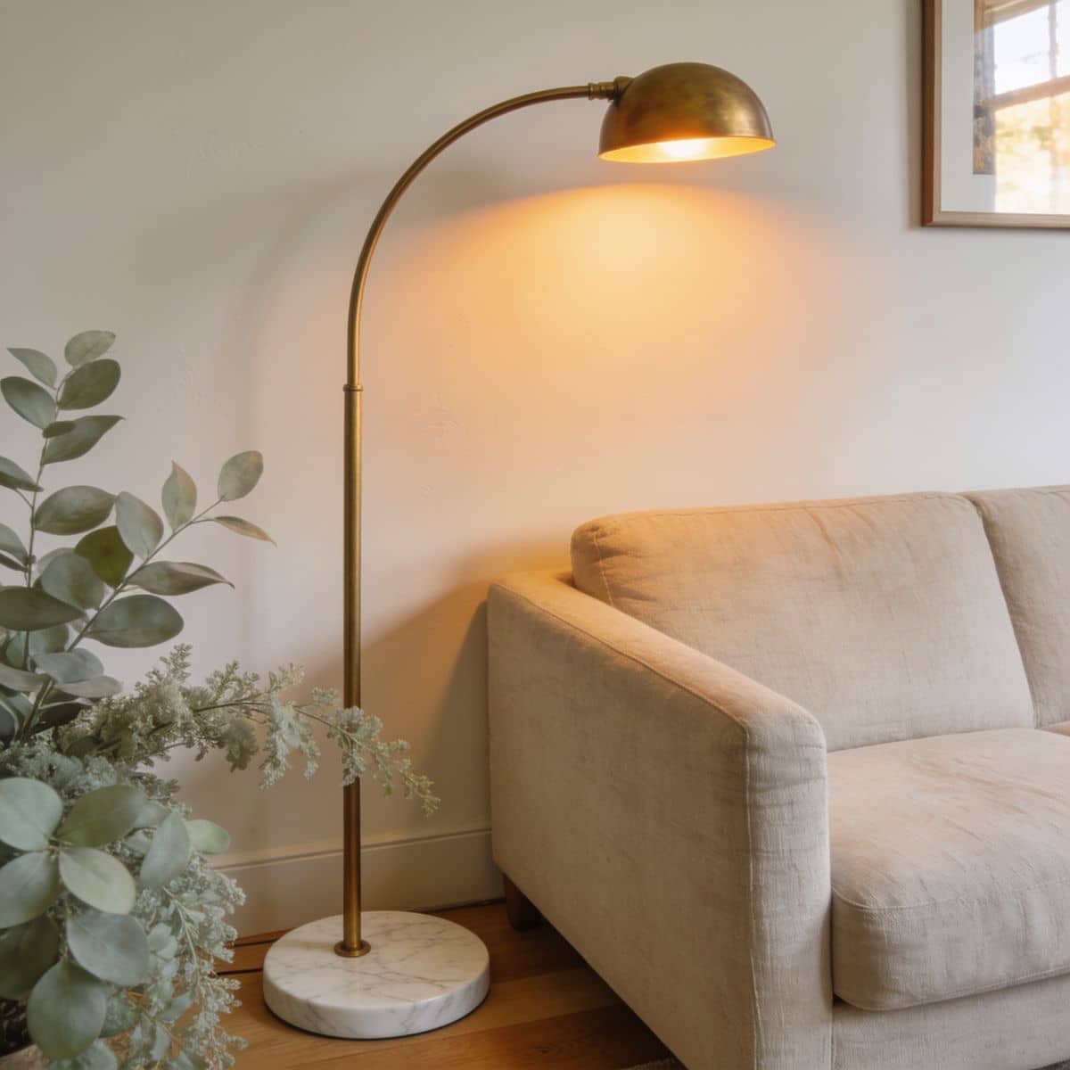 arc floor lamp with a faux-marble base and gold arm over a sofa