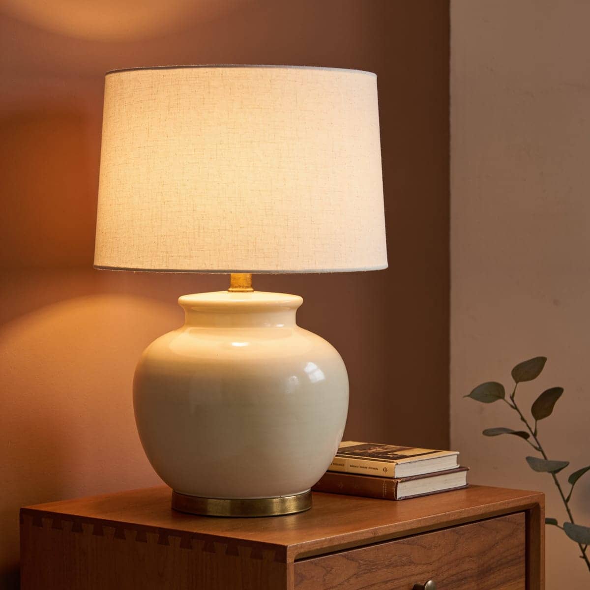 cream ceramic table lamp with a linen shade on a wood nightstand