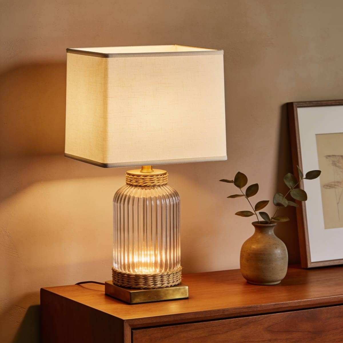 fluted ribbed glass table lamp with a warm bulb on a console