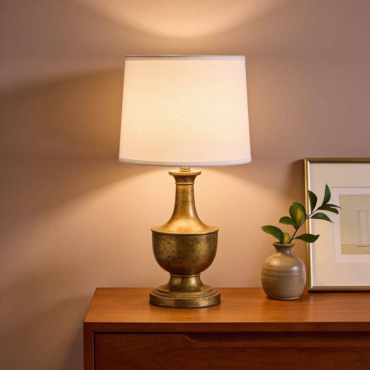 aged brass table lamp with a white linen shade on a dresser