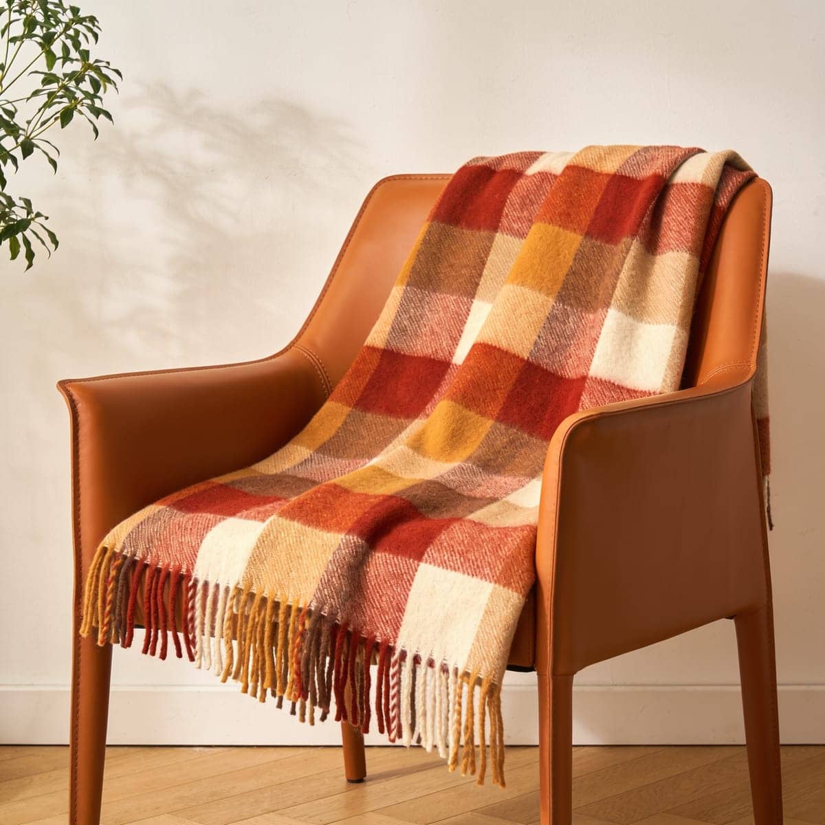 wool-blend plaid throw in rust and cream on a leather chair