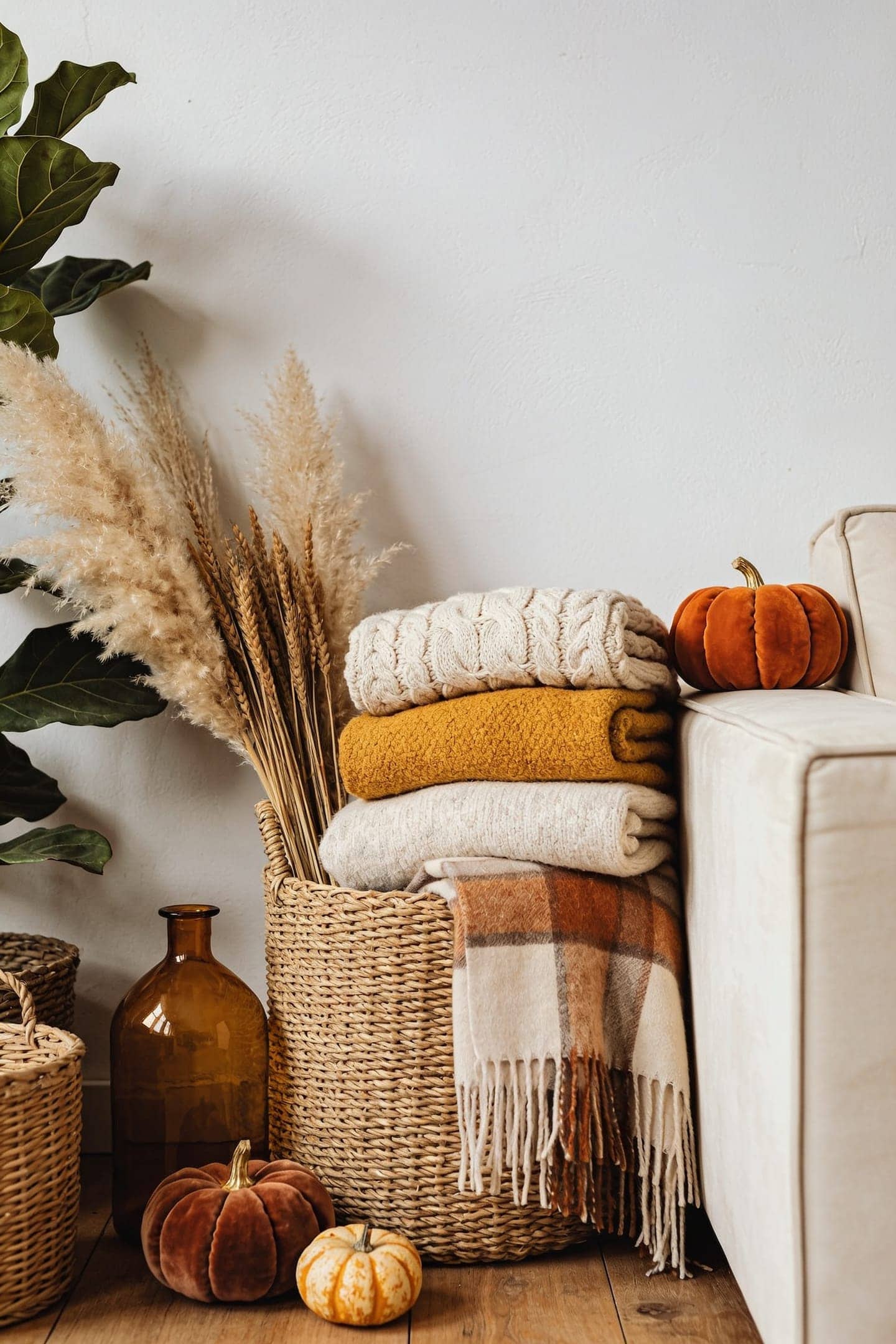 a woven basket of folded throws beside a couch
