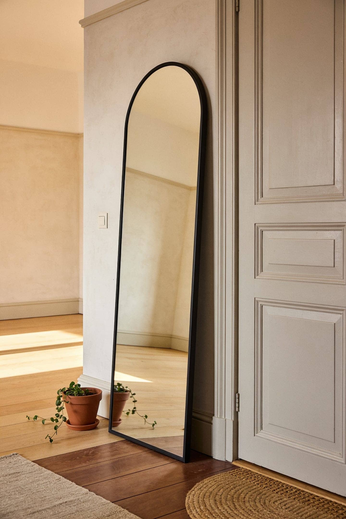 arched mirror leaning against an entryway wall beside a door frame