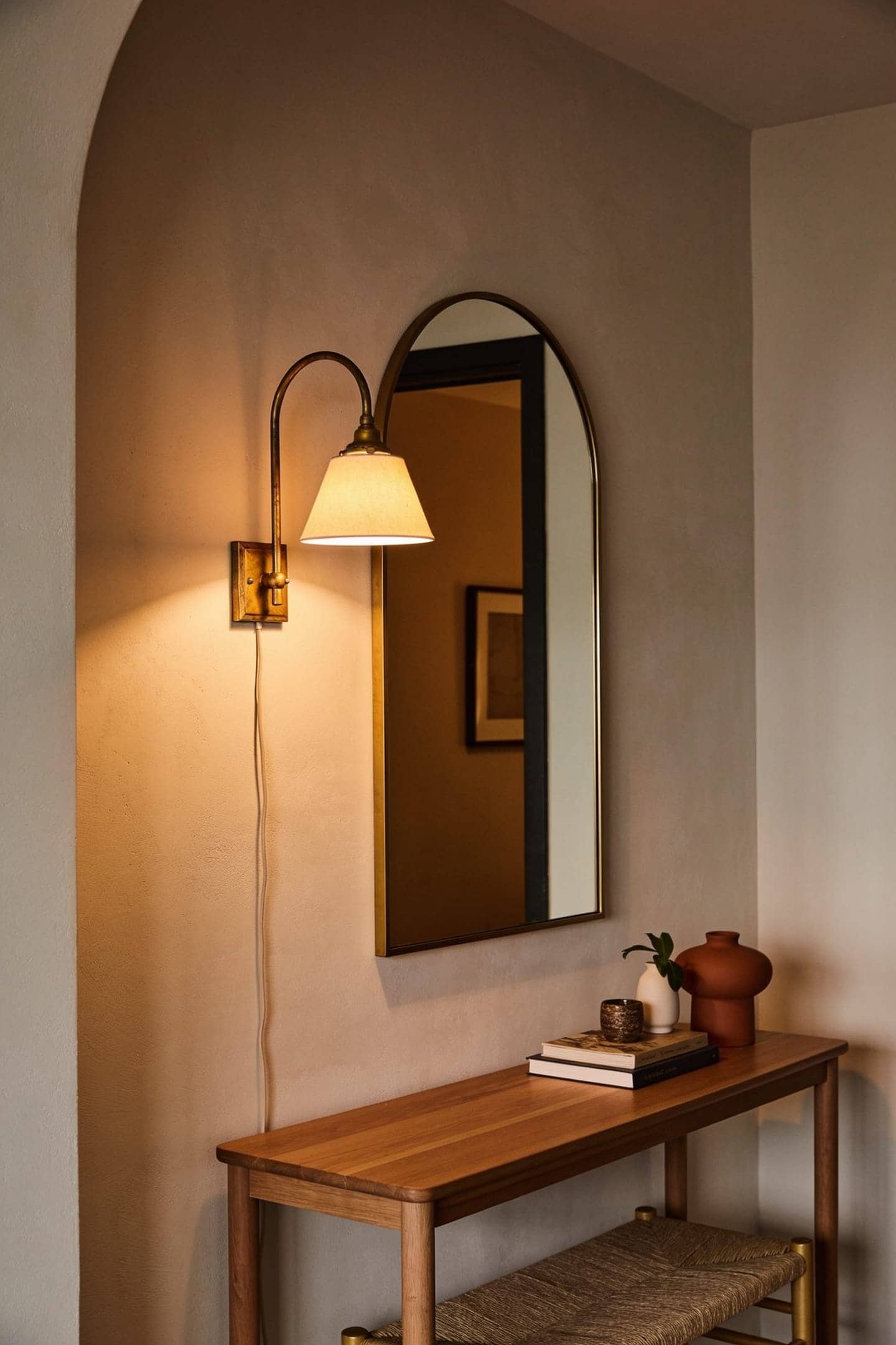 warm plug-in wall sconce glowing beside a mirror in a dim entryway