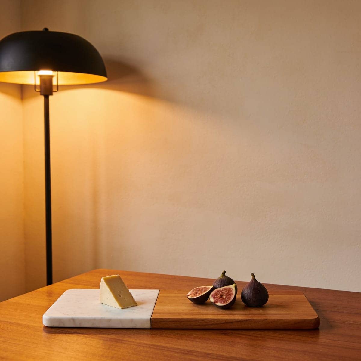marble and acacia wood serving board with cheese and figs