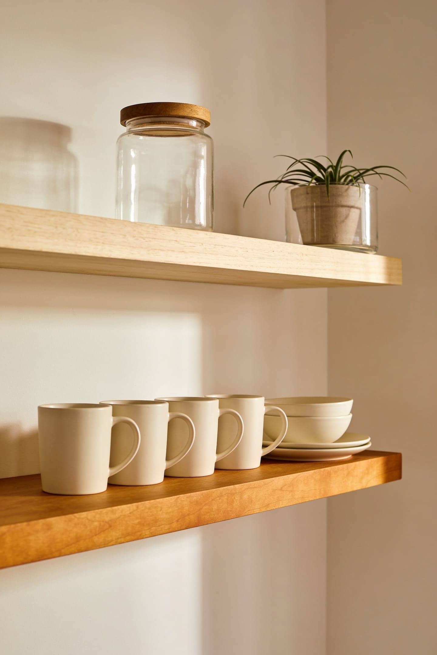 two open kitchen shelves, the lower one holding everyday mugs, the upper one styled sparsely