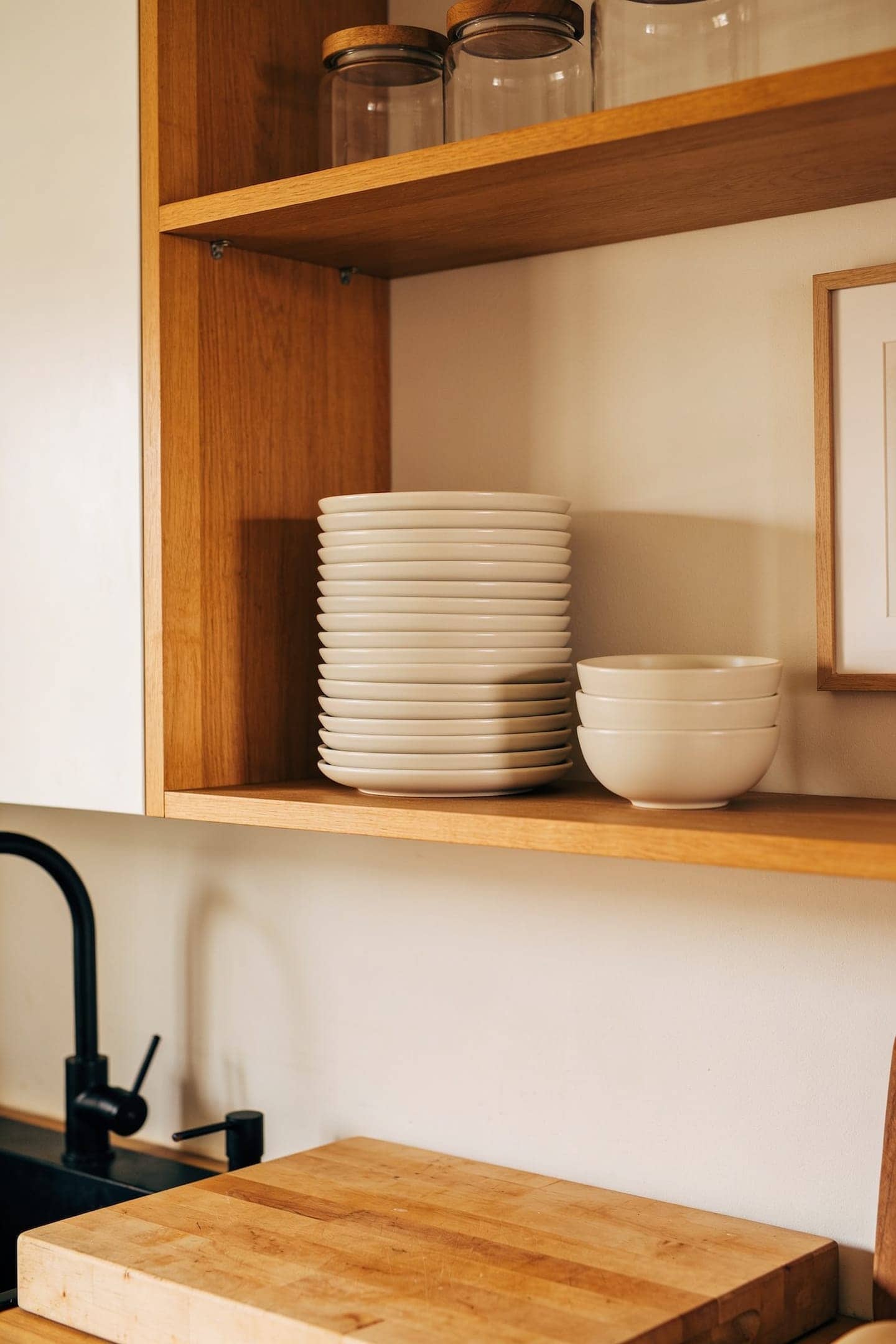 stack of matching white stoneware plates and bowls on an open kitchen shelf