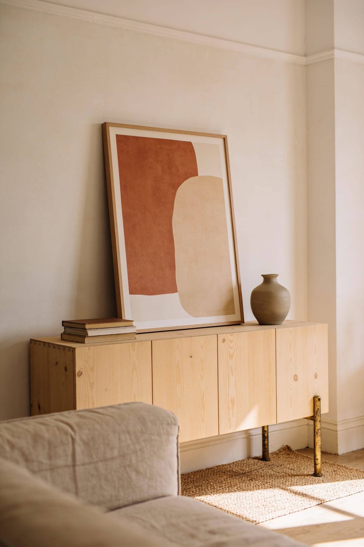 framed abstract art print in warm tones leaning on a living room console