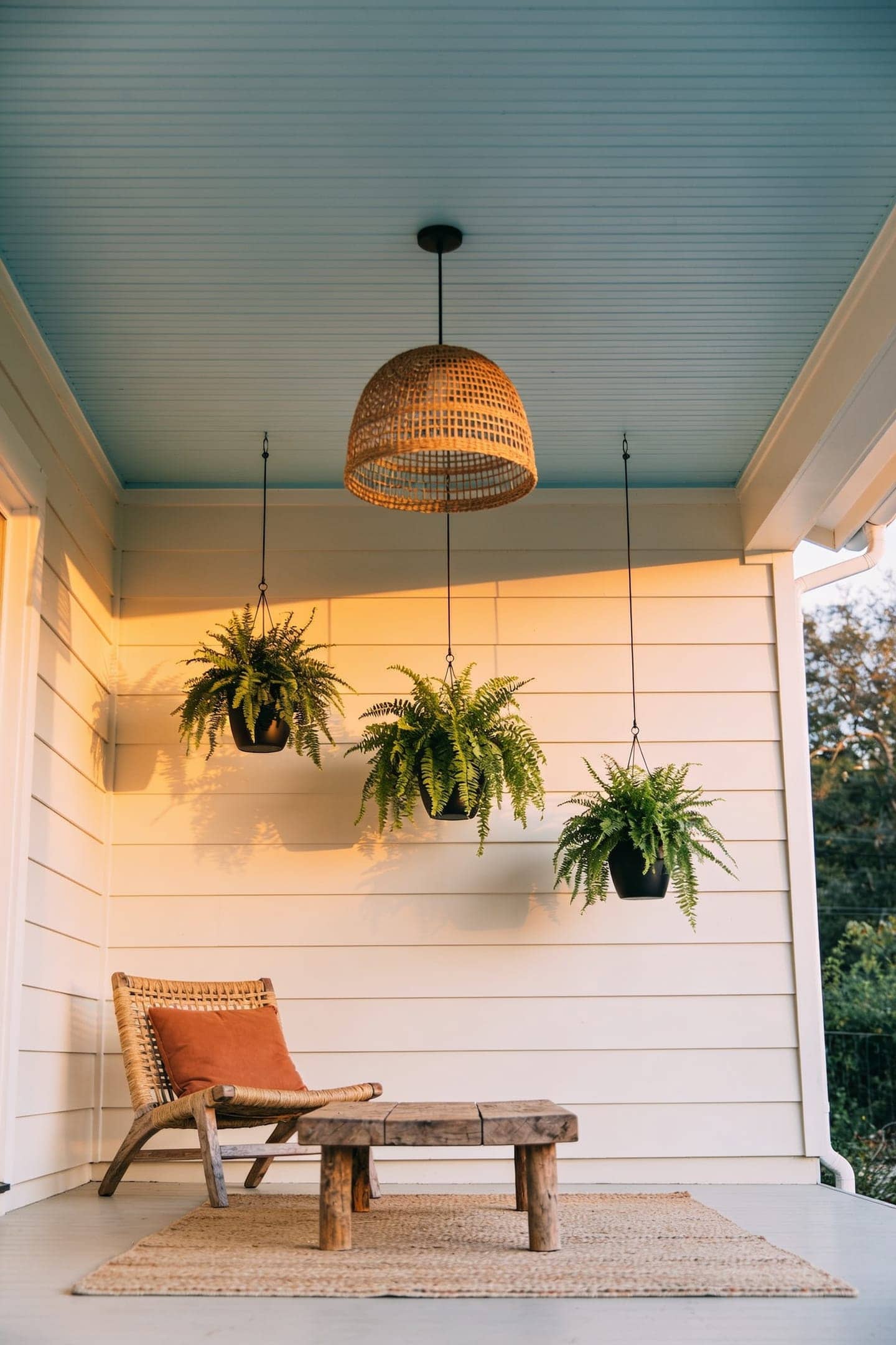 covered patio with a pale blue ceiling, a woven pendant and hanging ferns