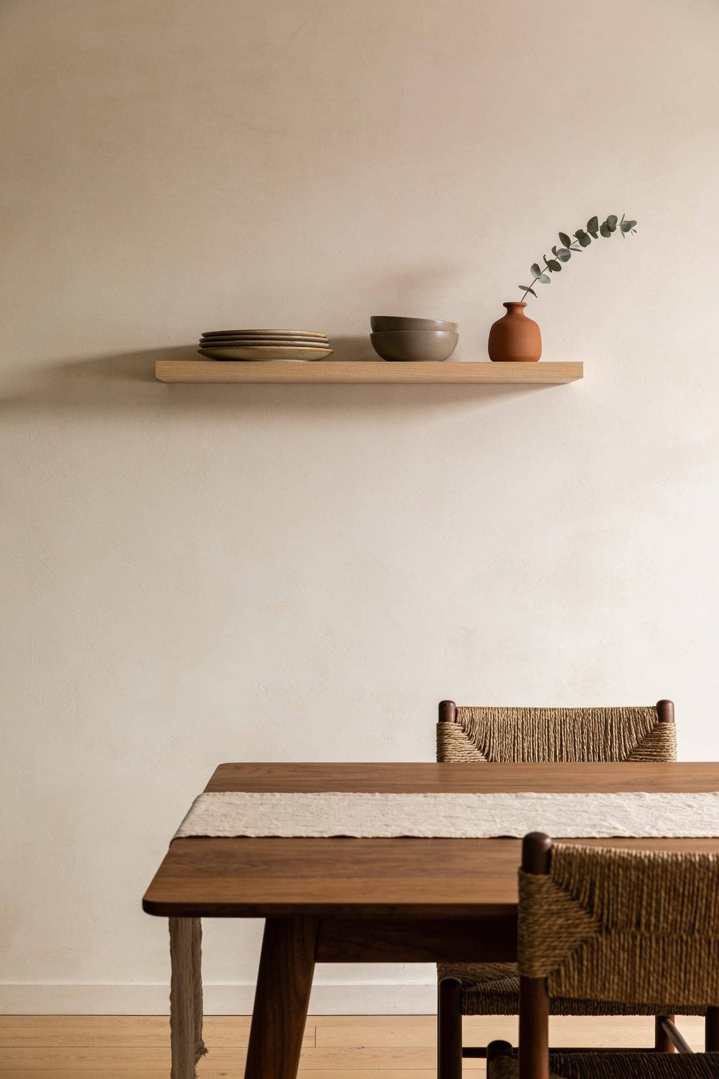 wall mounted shelf holding plates and glassware above a dining table