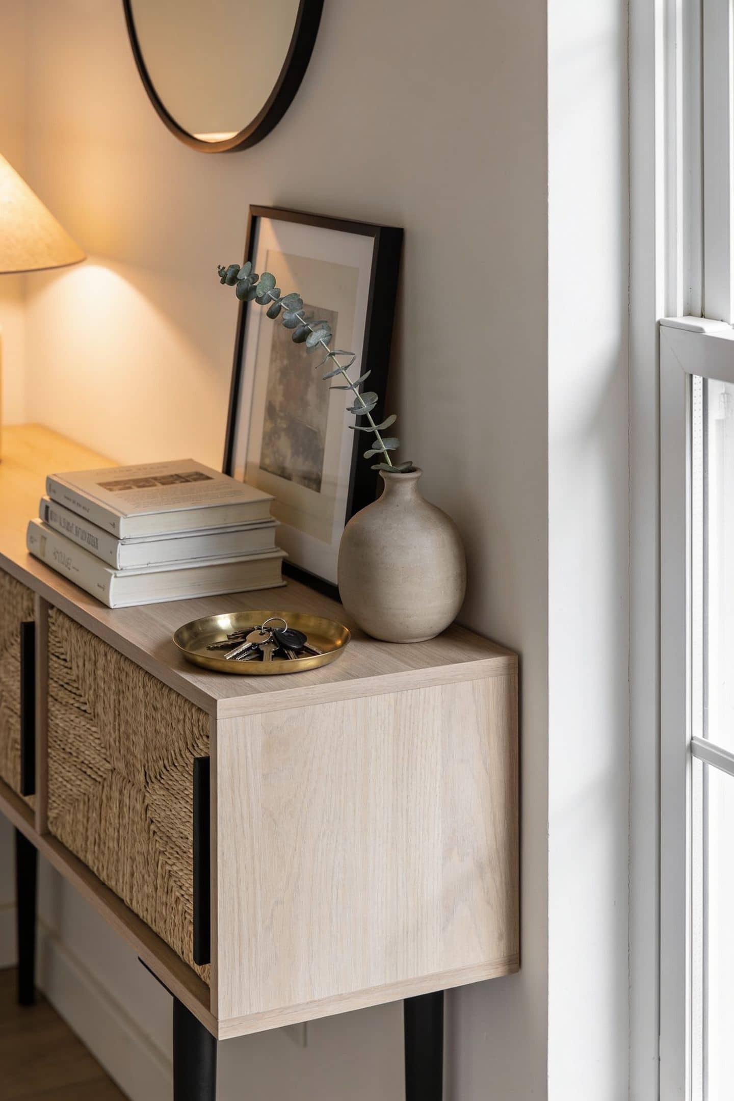 entryway console styled with a leaning frame, a small stack of books and a vase