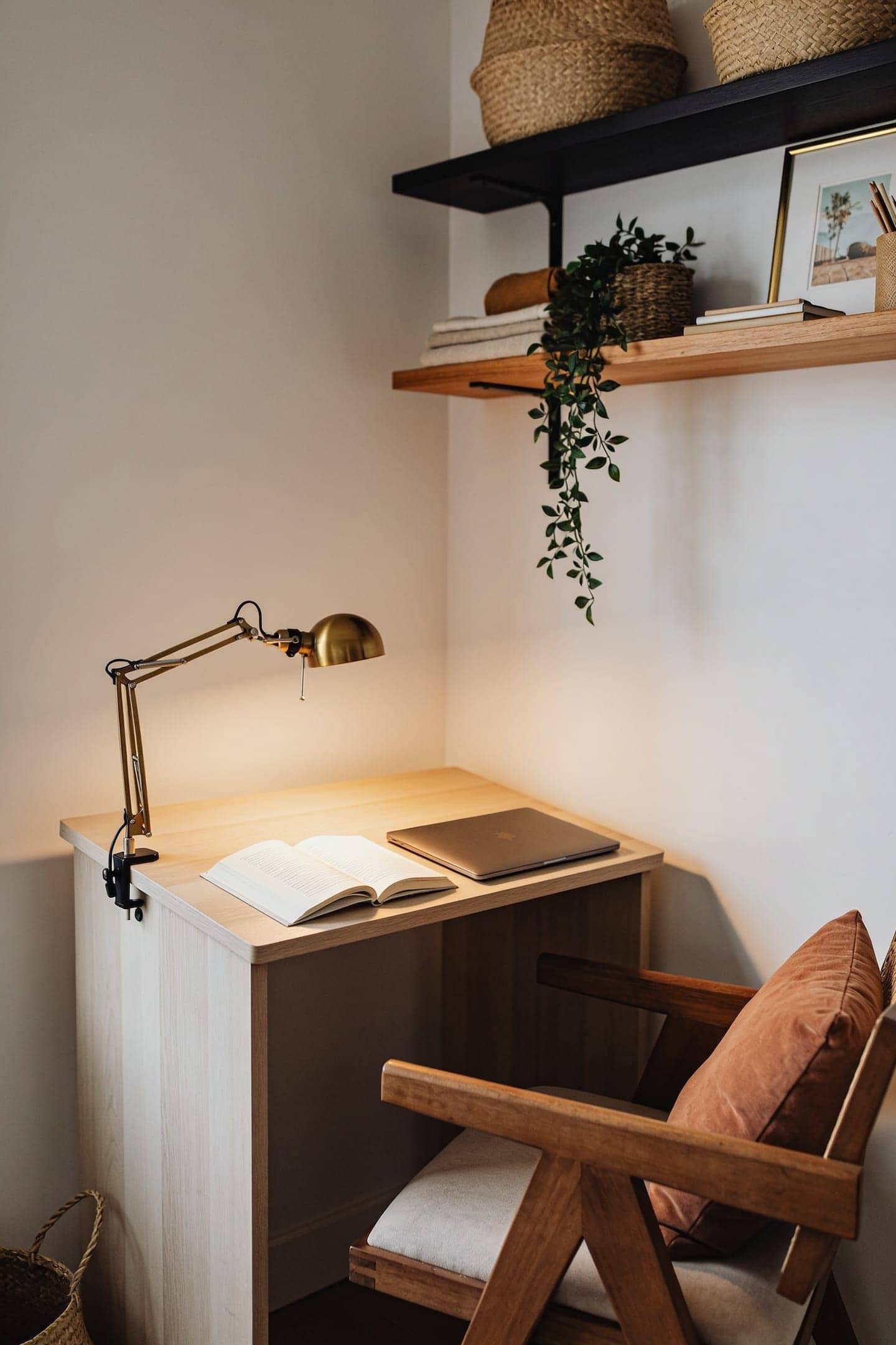 warm clamp task lamp lighting a small desk in the corner of a dim room